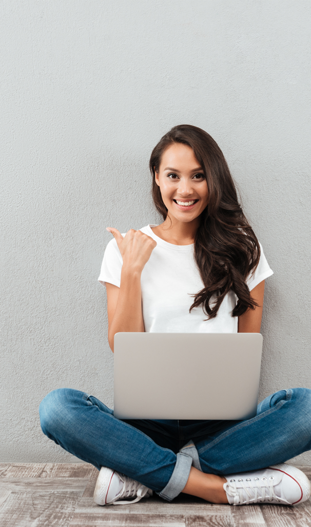 Happy young woman working on laptop while sitting on the floor with legs crossed isolated