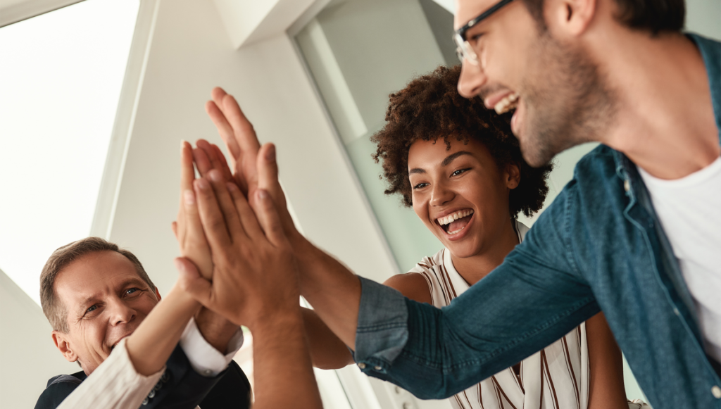 Business people giving each other high-five and smiling while working together in the modern office